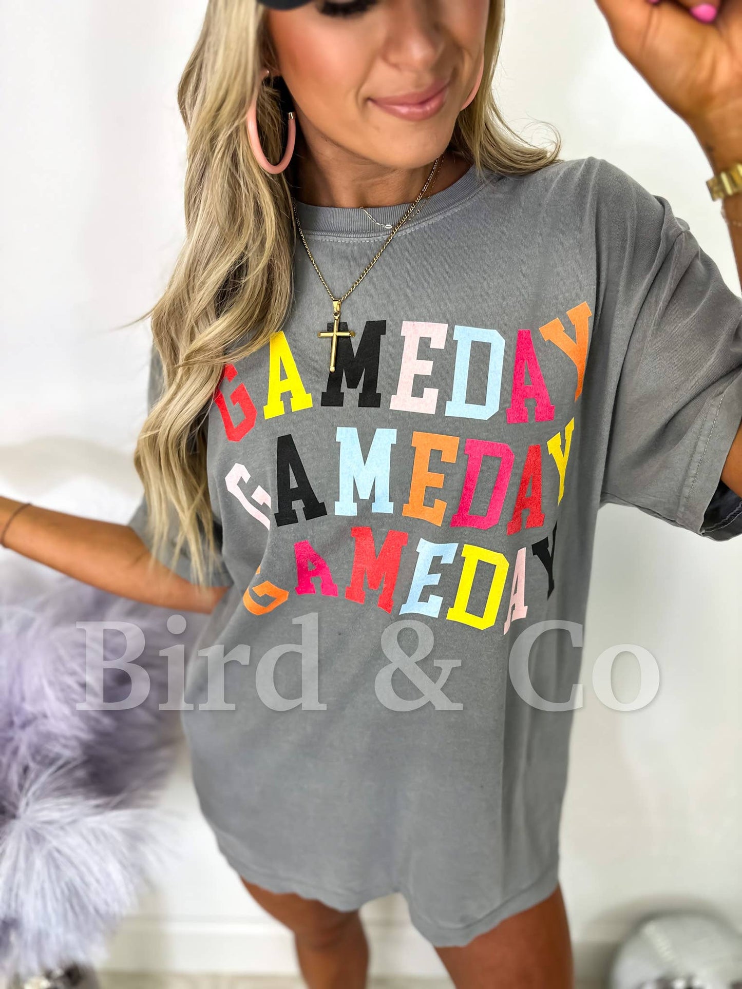Gray t-shirt with 'GAMEDAY' in colorful letters worn by a person.