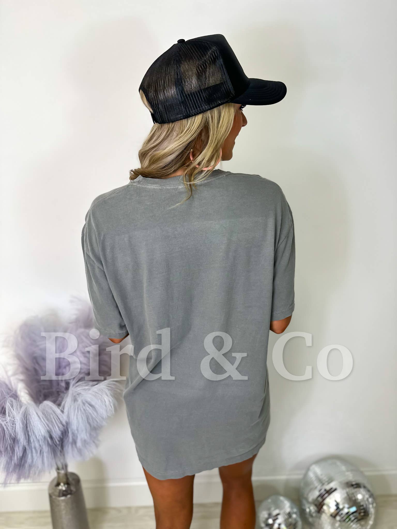 Person wearing a gray t-shirt and black cap with 'Bird & Co' branding.